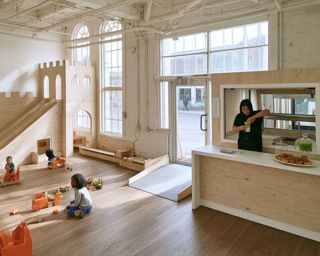 An open play room with a plywood climbing structure and a café counter